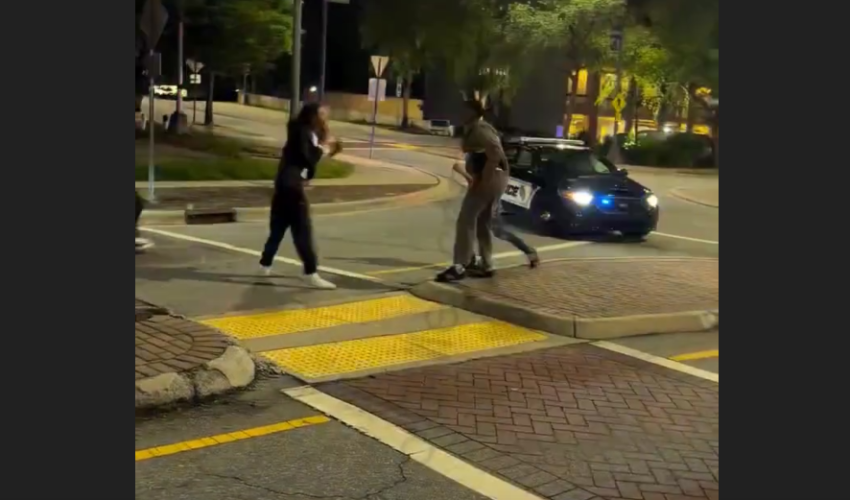Police Sits In His Car While Two Men Throw Hands Right In Front Of Him